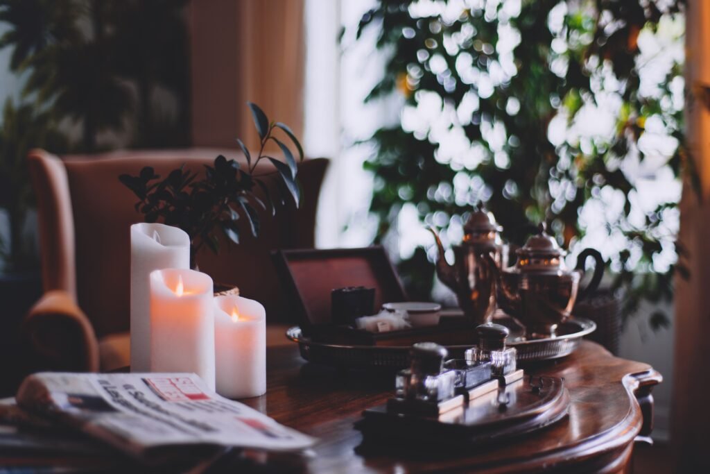 Warm, inviting living room with glowing candles, a teakettle, and lush indoor plants.