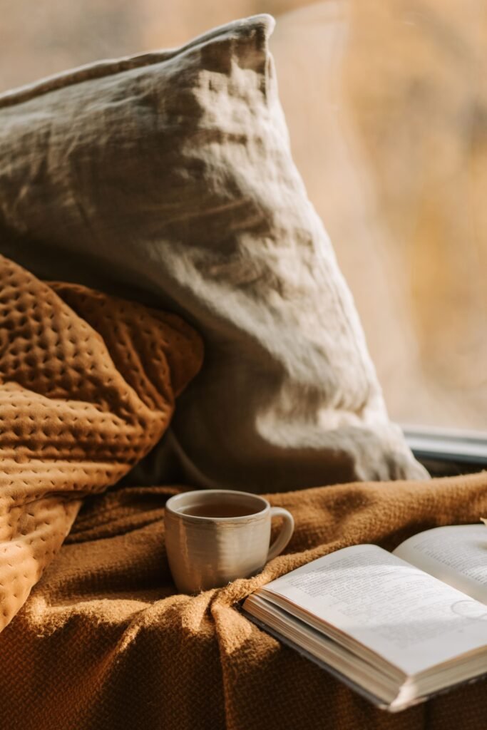 a hot cup of tea amidst an open book and cozy blankets