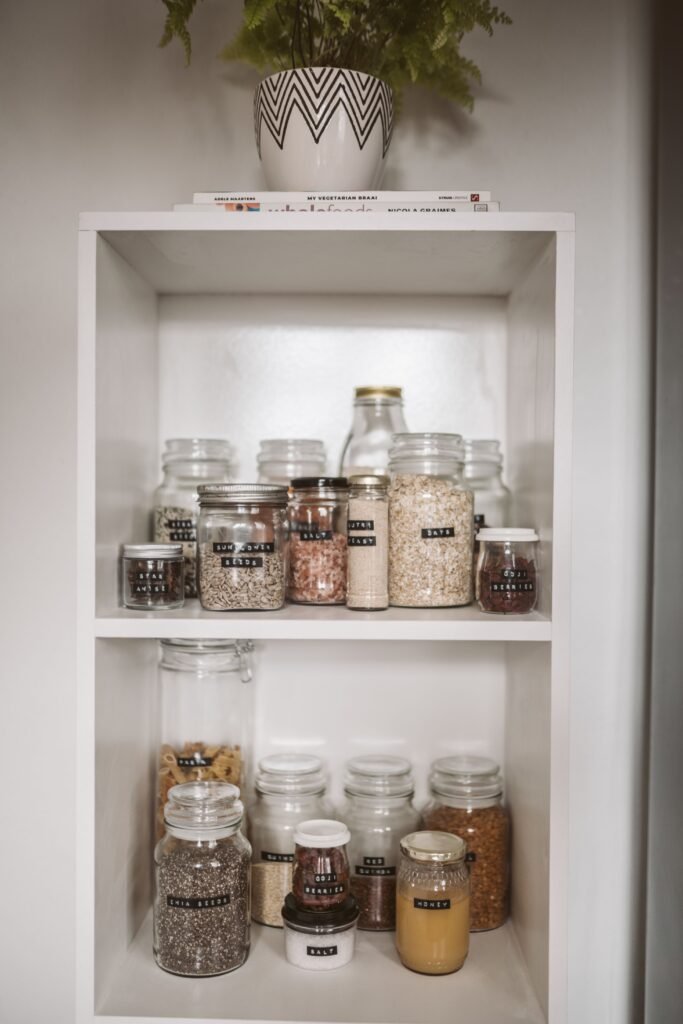 A pantry shelf with dry goods in labeled jars