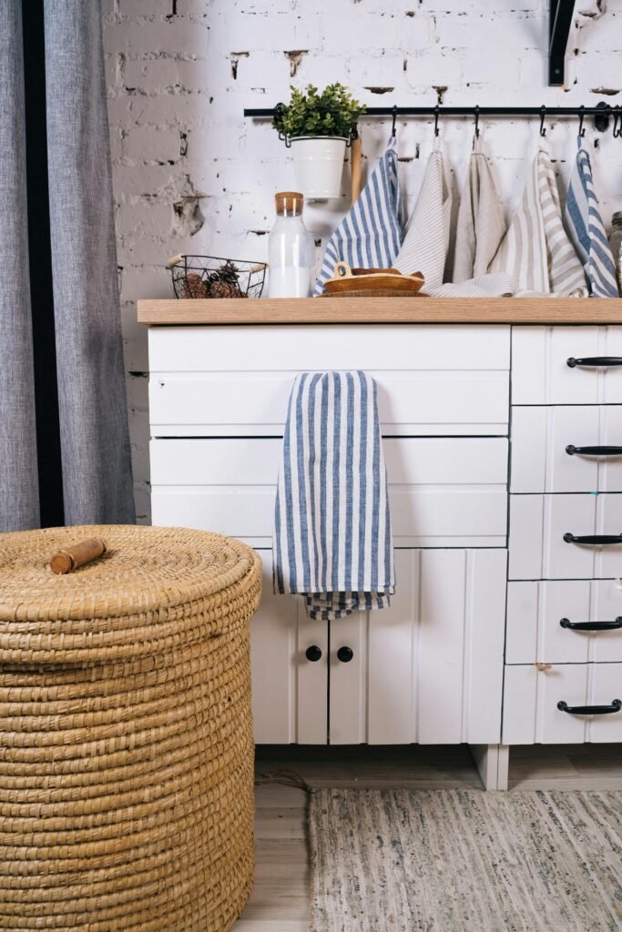 tea towels hung on the wall behind a kitchen counter and a large woven basket
