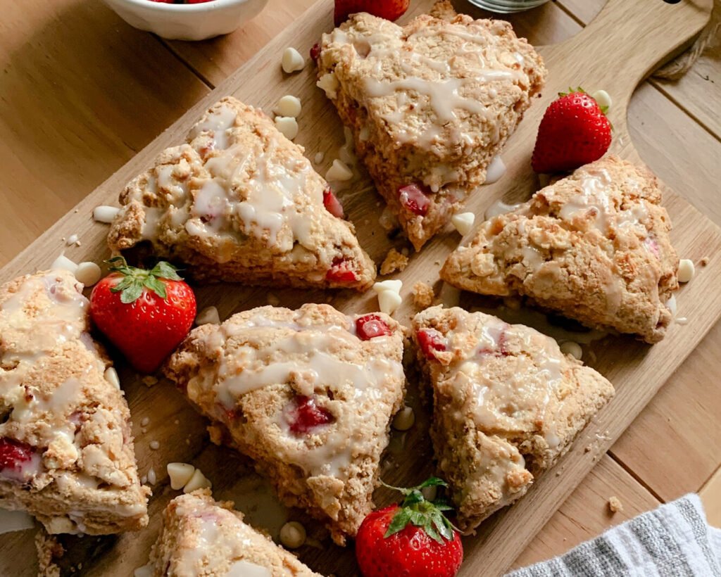 fresh milled white chocolate strawberry scones arranged on a wooden cutting board with strawberries and white chocolate on a wooden table