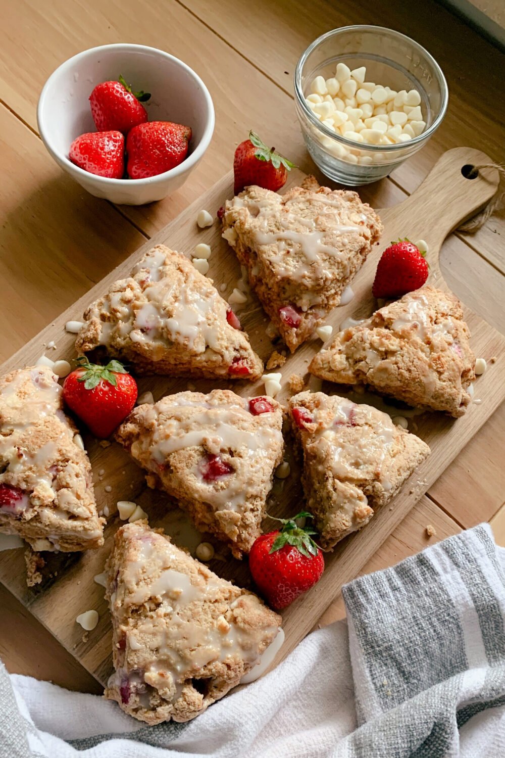 fresh milled white chocolate strawberry scones arranged on a wooden cutting board with strawberries and white chocolate on a wooden table