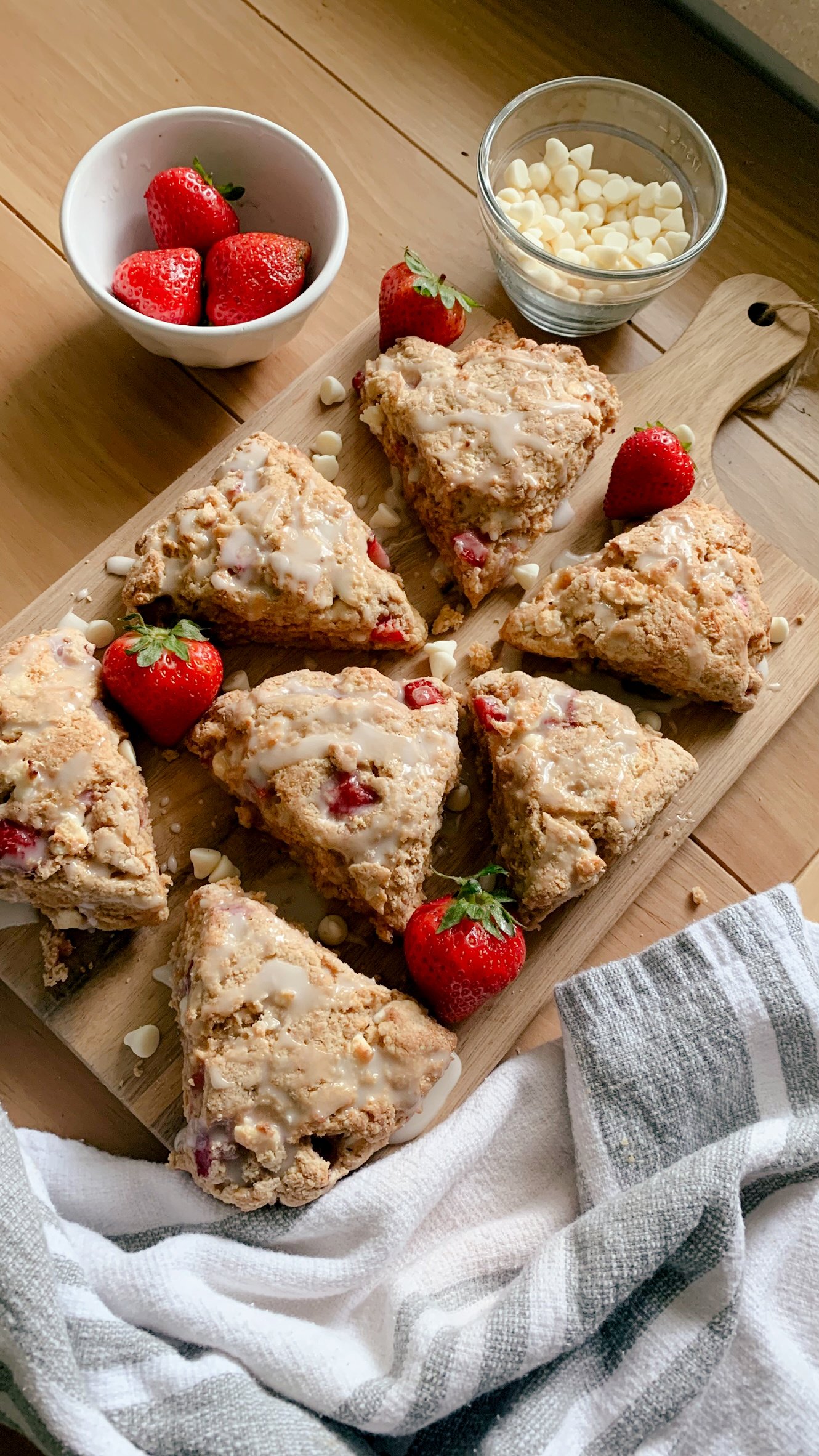fresh milled white chocolate strawberry scones arranged on a wooden cutting board with strawberries and white chocolate on a wooden table