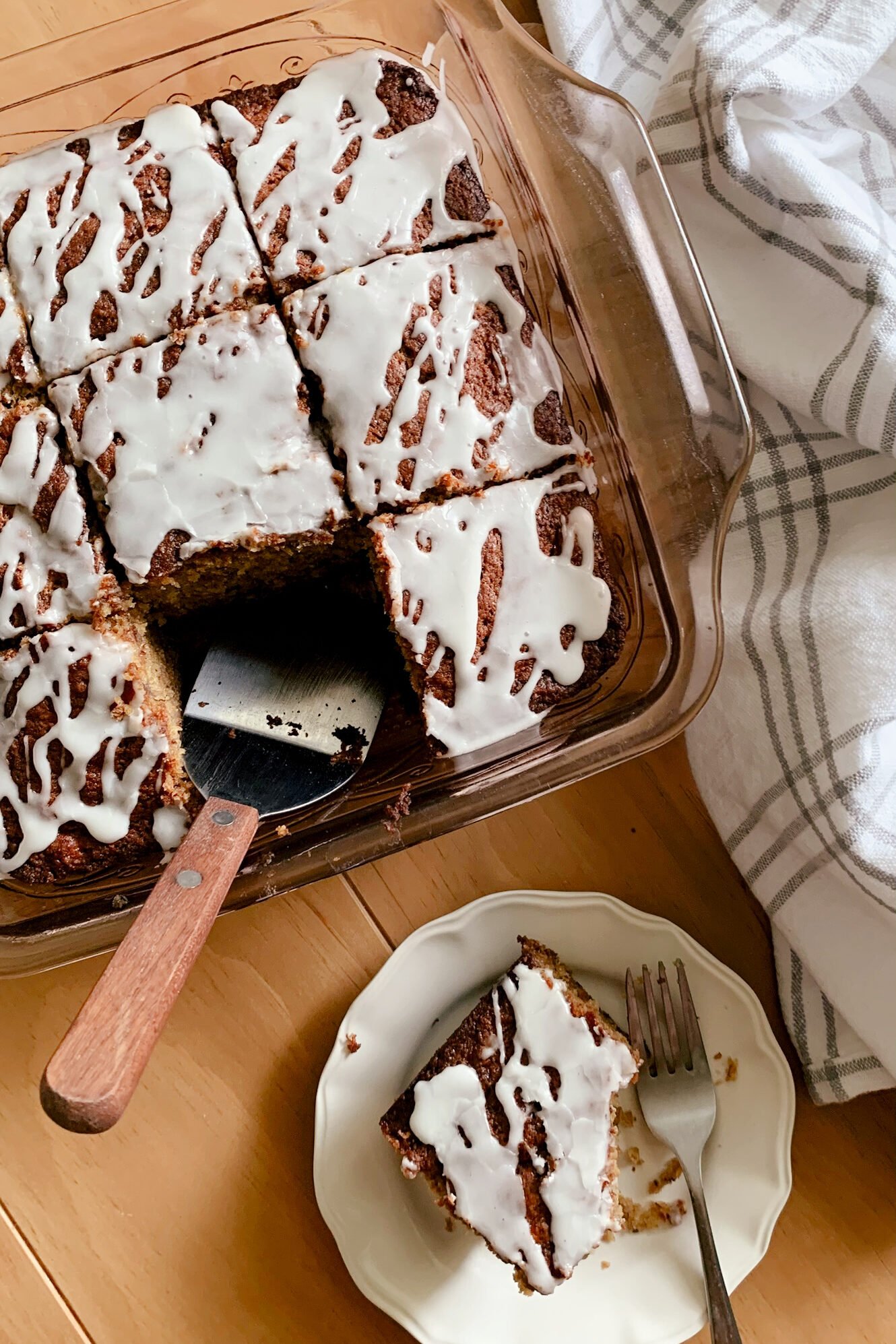 Fresh milled flour banana bread coffee cake next to a tea towel and a slice of cake on a plate with a fork