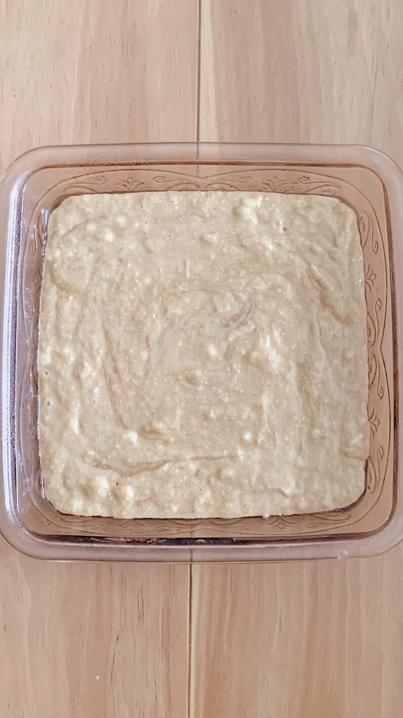 The fresh milled banana bread coffee cake batter poured out in a pink 8x8 baking dish