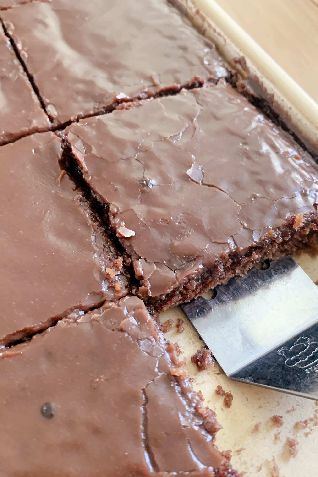 Fresh milled Texas Sheet cake cut into squares in a pan with a serving utensil lifting out a slice