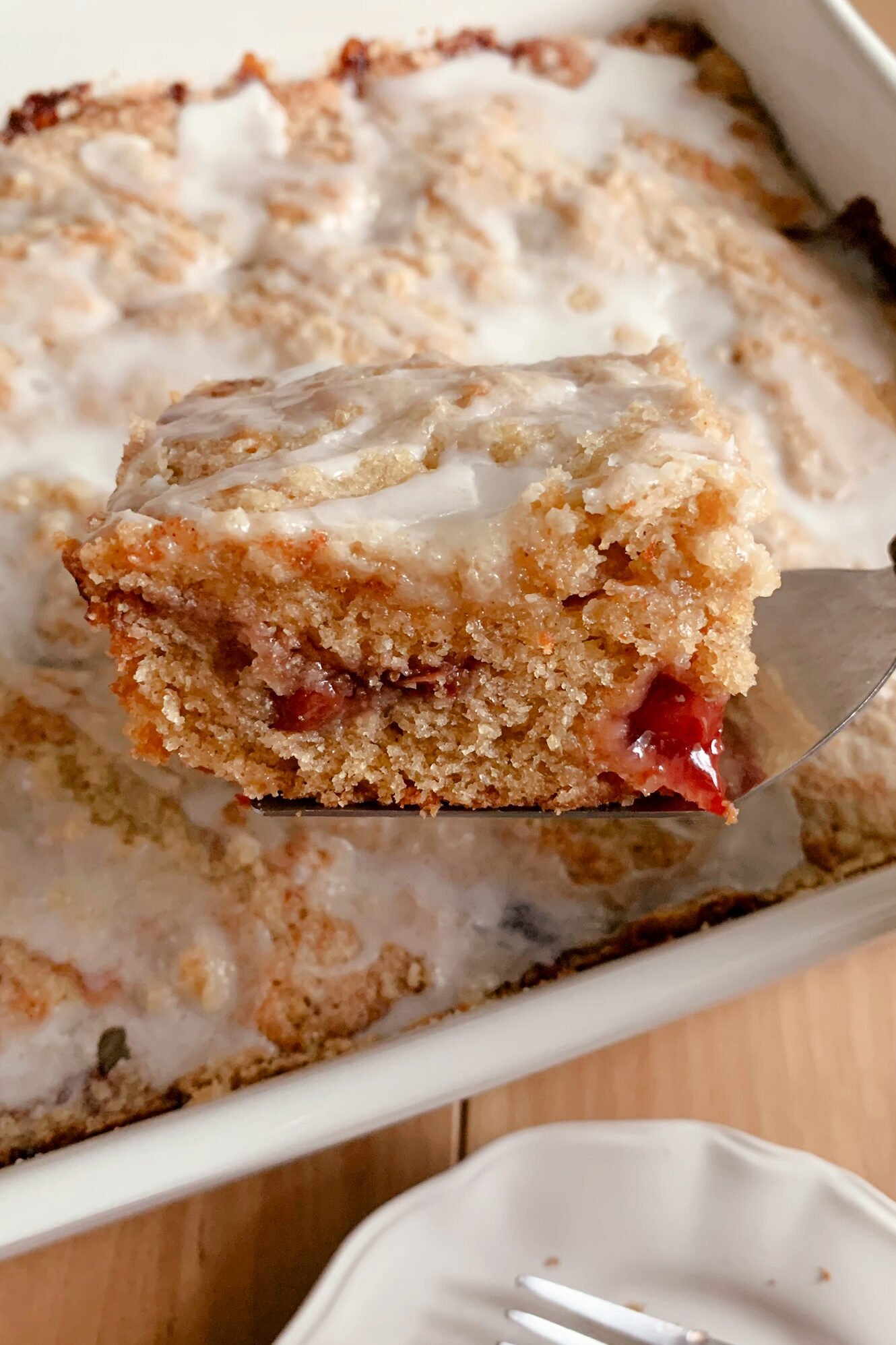 A slice of Fresh Milled Cherry Coffee Cake held up on a serving utensil
