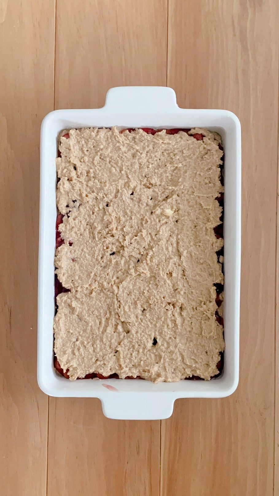 The fresh milled cherry coffee cake ready for the streusel topping, on a wooden surface