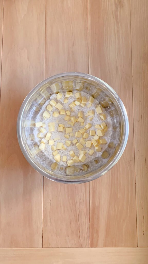 Dry ingredients and butter cut into cubes to make fresh milled cherry coffee cake on a wooden surface