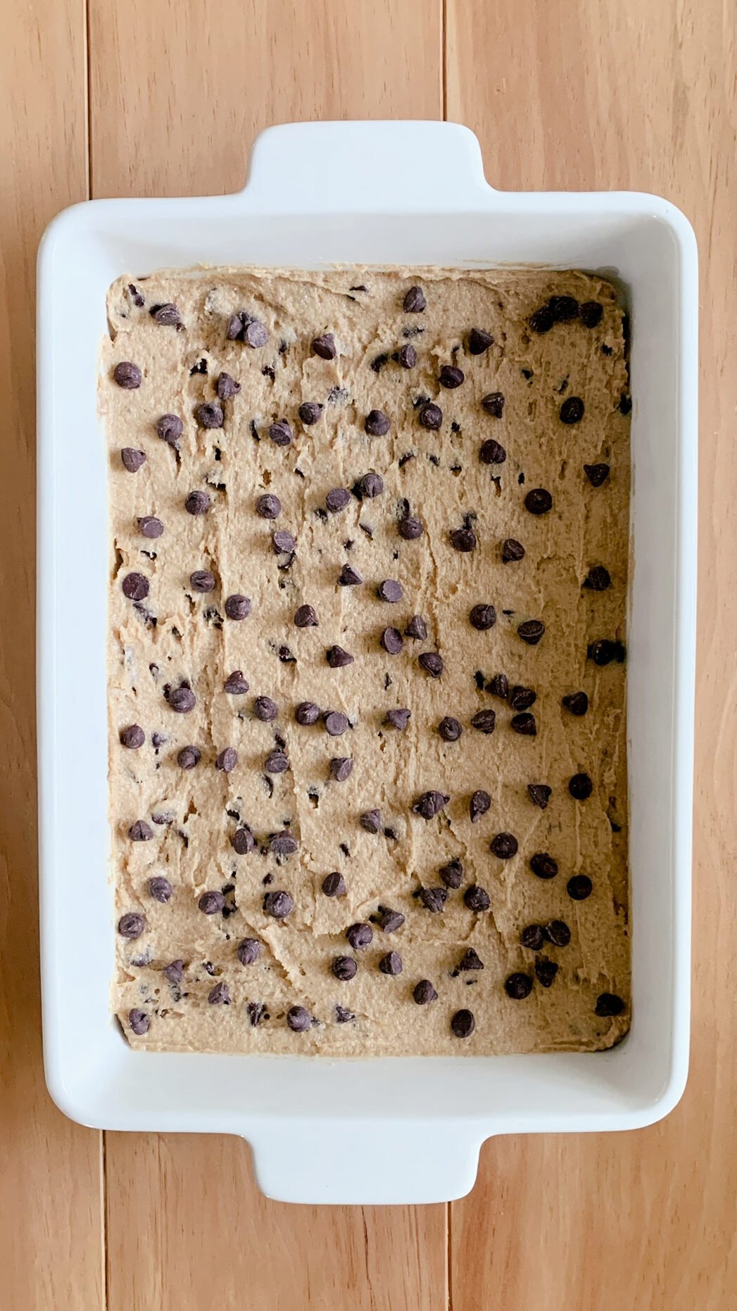 fresh milled chocolate chip cookie bar dough spread evenly in a white 9x13 baking dish