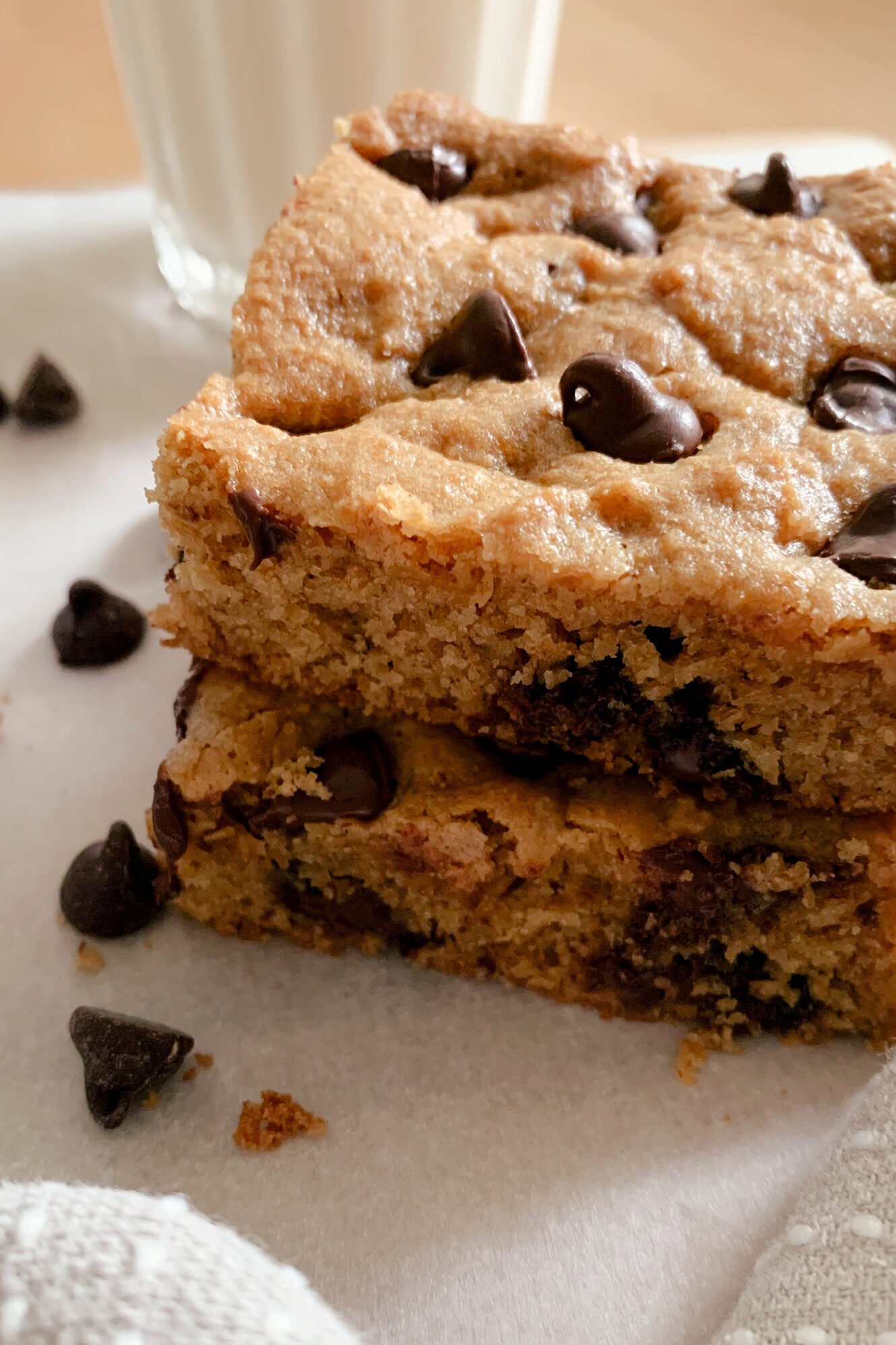 a close up view of fresh milled chocolate chip cookie bars next to a glass of milk