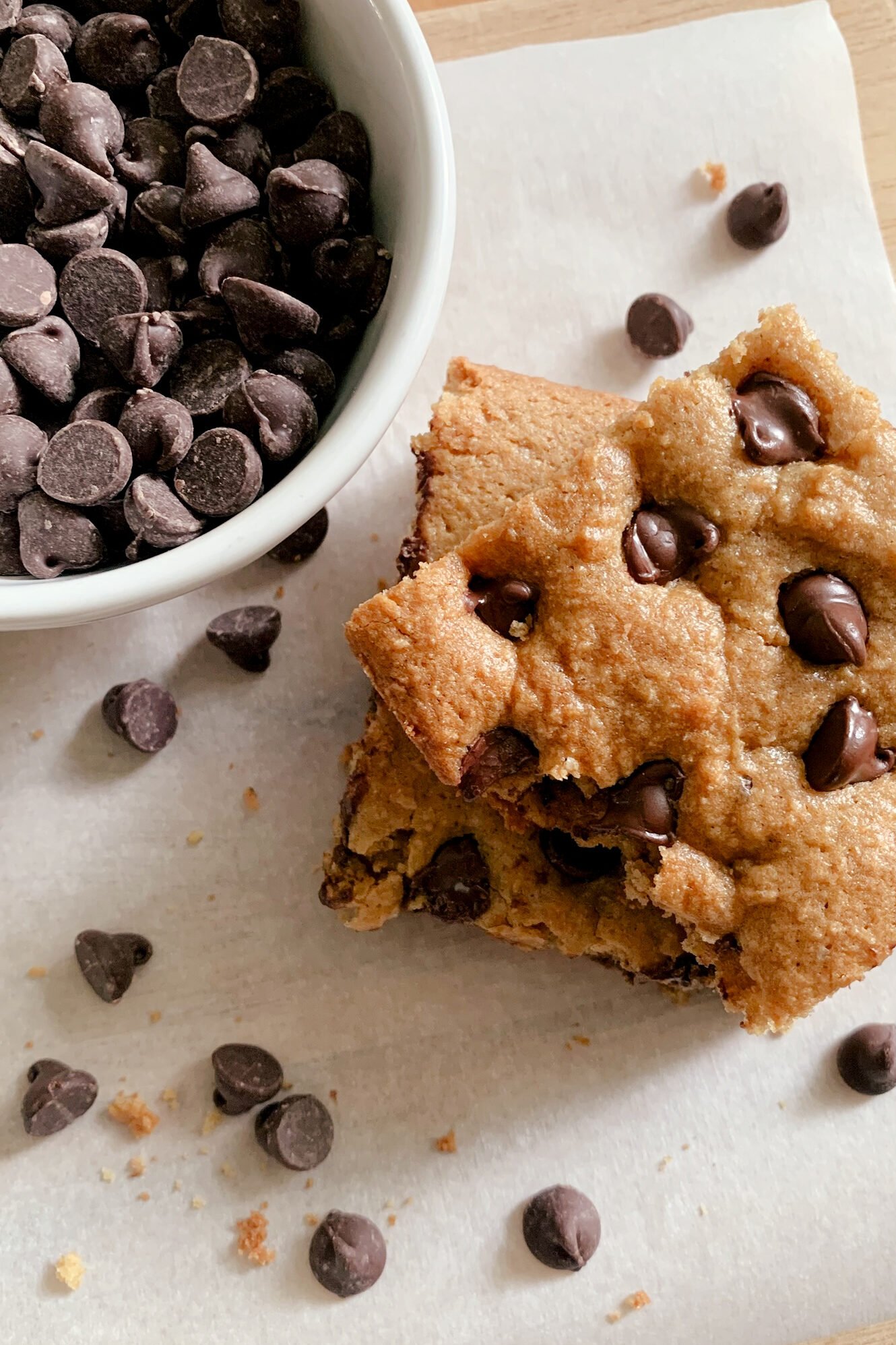a close up view of fresh milled chocolate chip cookie bars next to a bowl of chocolate chips