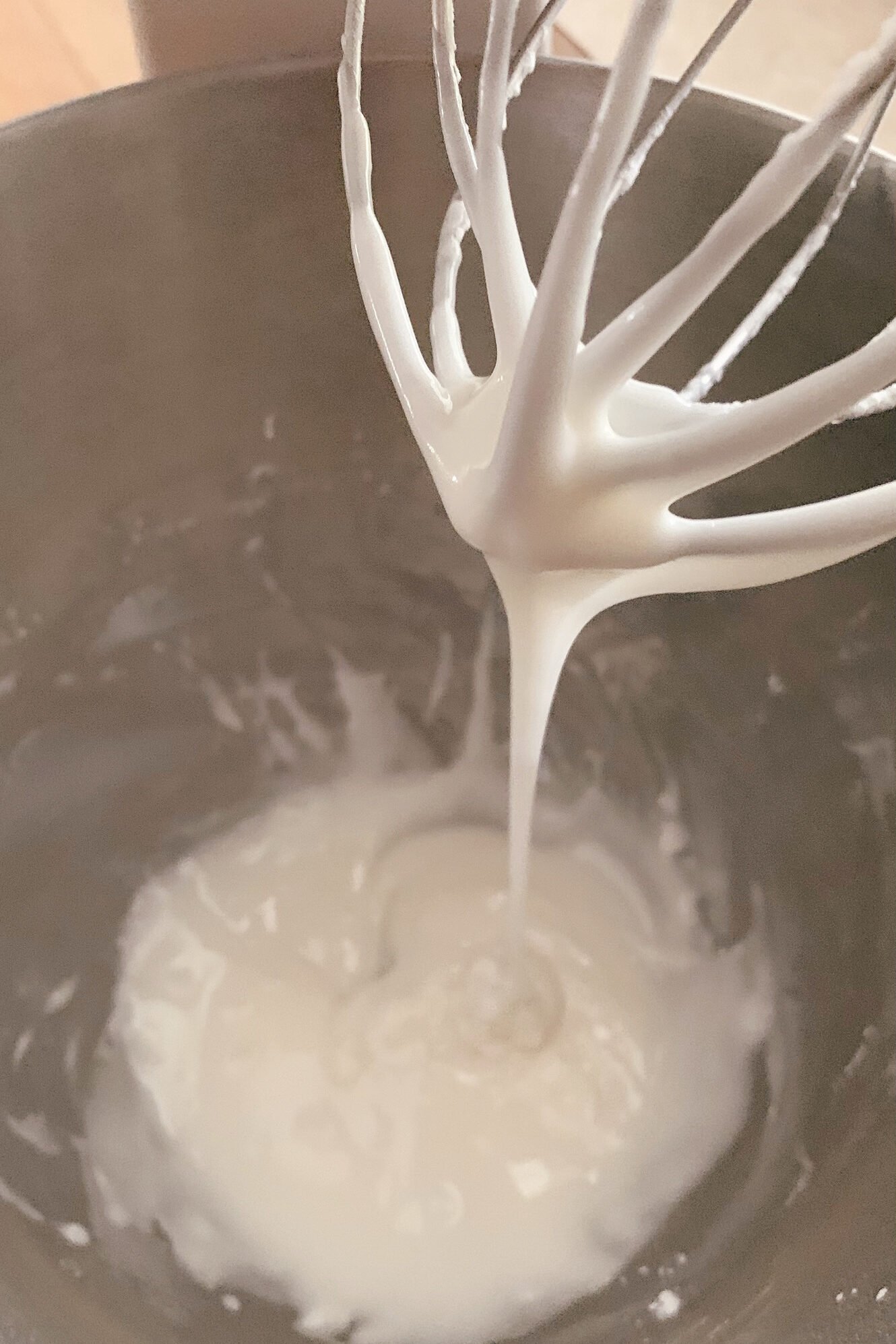 powdered sugar glaze in a stand mixing bowl drizzled by a whisk