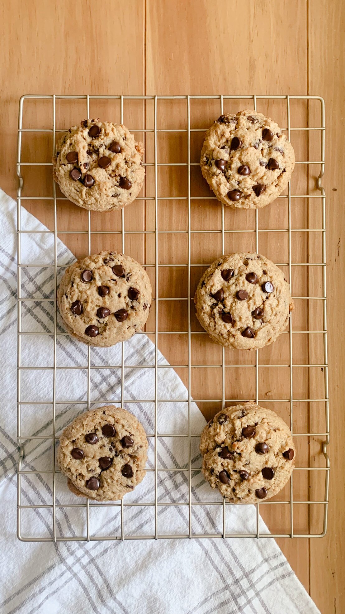 6 fresh milled peanut butter oatmeal chocolate chip cookies on a cooling rack with a tea towel