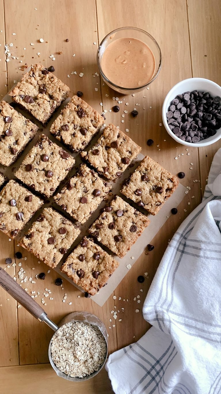 fresh milled peanut butter chocolate chip cookie bars on a wooden table next to a tea towel